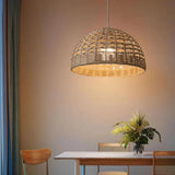 Rattan ceiling light with an open woven dome shade lit in a warm interior