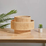 Small rattan drum pendant light hung above a table with objects