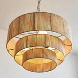 Rattan drum pendant light seen from below, the tiers lit as concentric rings