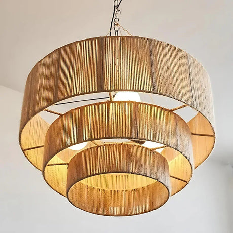 Rattan drum pendant light seen from below, the tiers lit as concentric rings