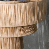 Close view of the woven straw and the hanging fringe of the drum shade