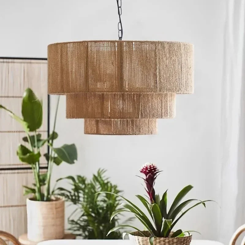 Rattan drum pendant light with three fringed tiers lit above a row of plants