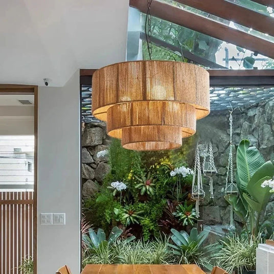 Rattan drum pendant light hung in front of a window beside plants