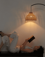 Black arc lit over a bench at night, the woven shade glowing above a reader