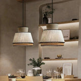 Three woven rattan pendants lit above a kitchen counter