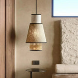 Woven rattan pendant hung in a living room against a stone wall