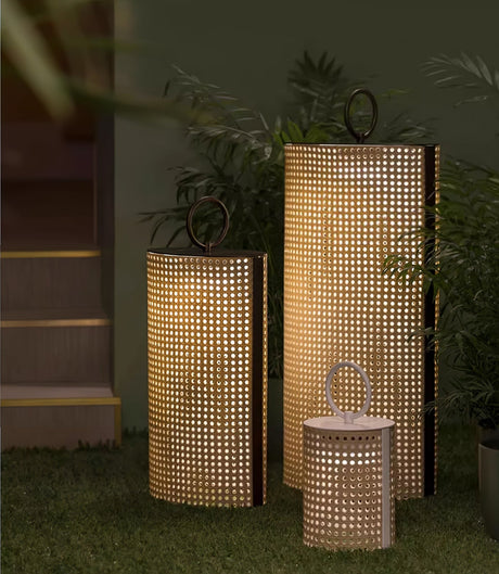 Lanterns lit beside a garden path with tall planting behind them