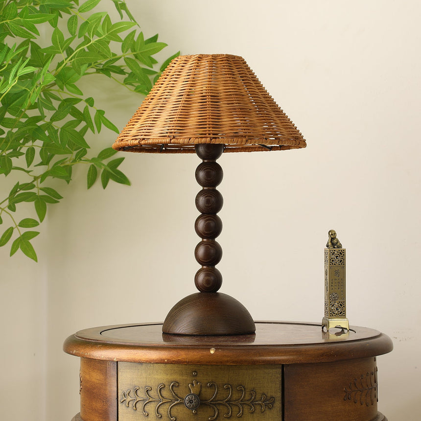 Rattan shade lamp lit and seen from a slight angle on a side table