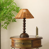 Rattan shade lamp lit on a side table beside a pale armchair
