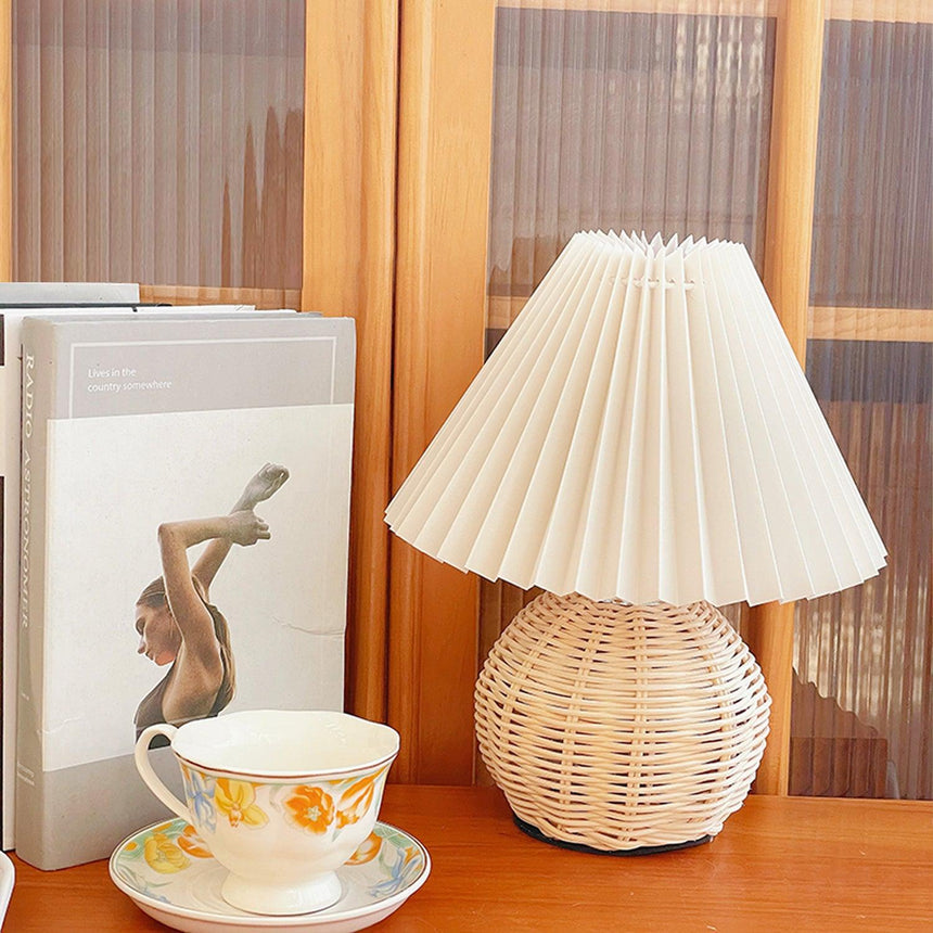 Rattan table lamp beside a wooden screen with a teacup and books