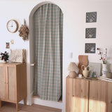 Rattan table lamp on a chest in an entryway beside an arched door