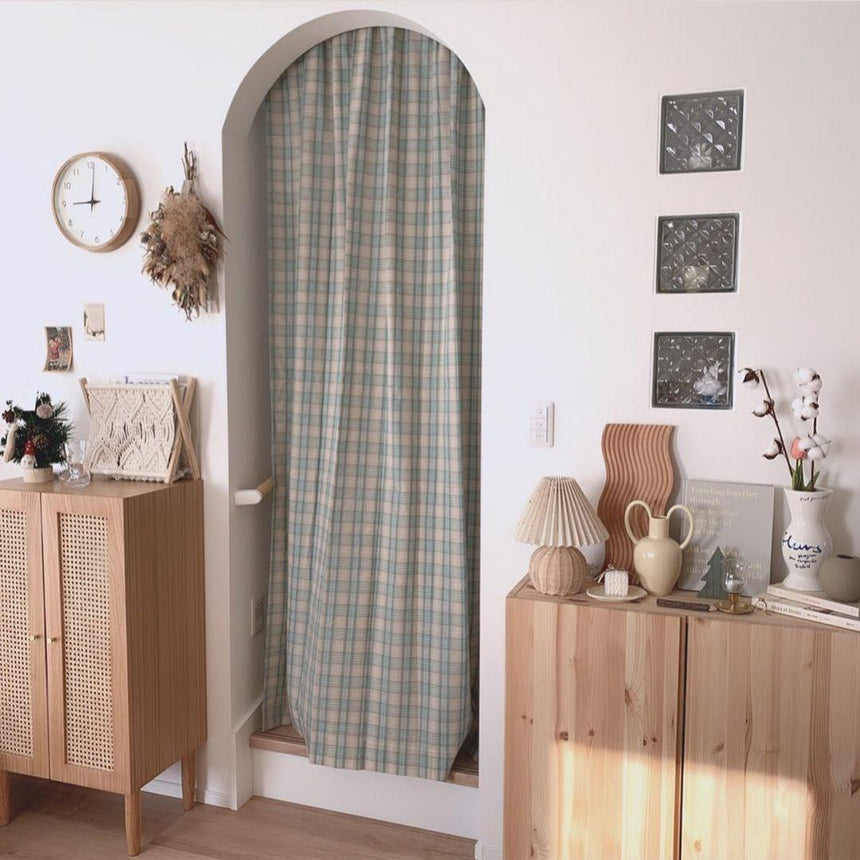 Rattan table lamp on a chest in an entryway beside an arched door