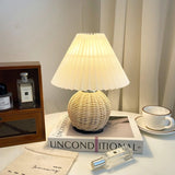 Rattan table lamp lit on a dressing table beside a perfume bottle