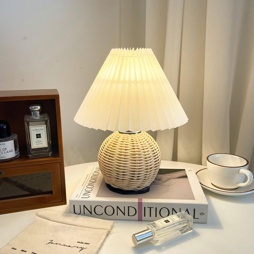 Rattan table lamp lit on a dressing table beside a perfume bottle