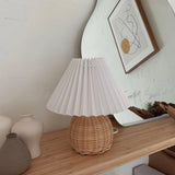 Rattan table lamp on a wooden shelf below a framed print