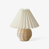 Rattan table lamp with a woven globe base and pleated shade, plain ground