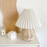 Rattan table lamp on a white table beside a fluted wooden panel