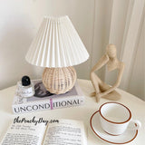 Rattan table lamp on a side table beside an open book and a cup