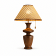 Rattan table lamp with the hand woven shade lit, plain background