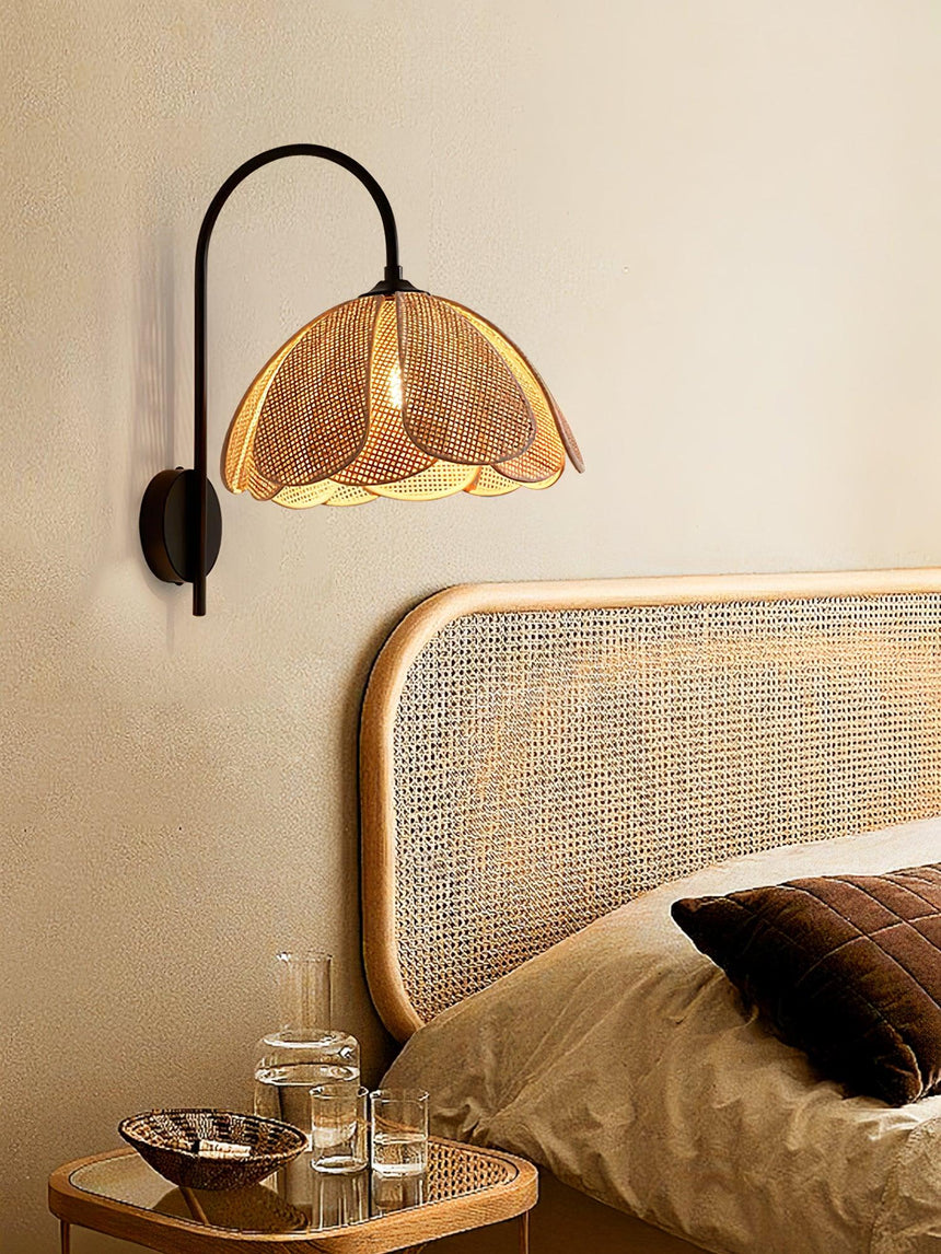 The rattan sconce lit above a cane headboard and a brown cushion