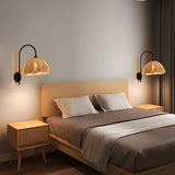 A pair of rattan petal sconces lit on either side of a bed with wood nightstands