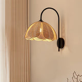 The rattan sconce lit on a beige wall beside a sheer curtain