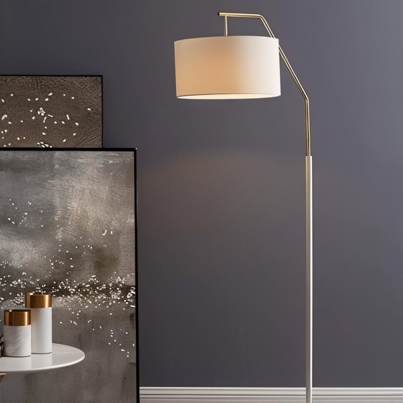 The lamp lit beside large artwork leaning on a wall, a small round table nearby