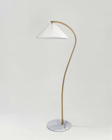 Brass floor lamp with a curved stem and a white pleated shade on a marble base