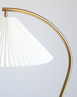 The white pleated shade seen close, the brass stem curving in under the folds
