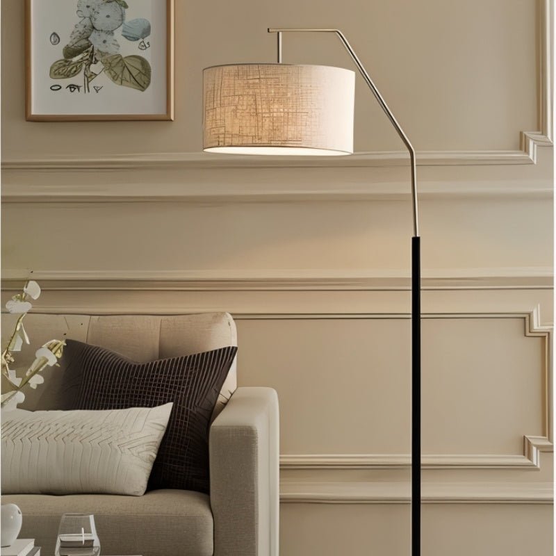 The lamp lit beside a sofa with cushions, a molded wall and a framed print above