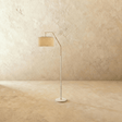 A slim white stem with a short angled arm holding a fabric drum shade above a round base