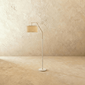 A slim white stem with a short angled arm holding a fabric drum shade above a round base