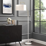 The lamp lit beside a window and a dark console table with books and a vase