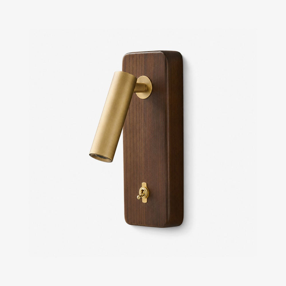 Reading light wall sconce with a brass head on a tall ash wood plate