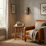 Reading sconce lit in a reading corner above a side table and armchair