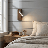 Reading sconce lit on a painted shiplap wall above a bedside table