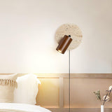Sconce lit above a bed, the beam falling across white pillows below