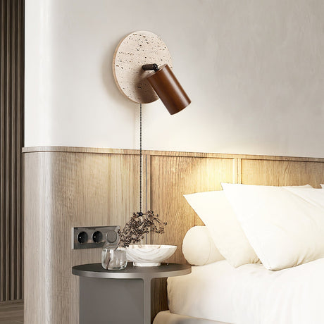 Sconce lit beside a slatted headboard above a nightstand with a small tray