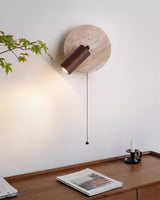 Sconce lit above a console holding an open magazine beside green leaves