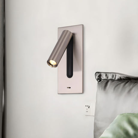 The nickel reading light above a bed with green pillows