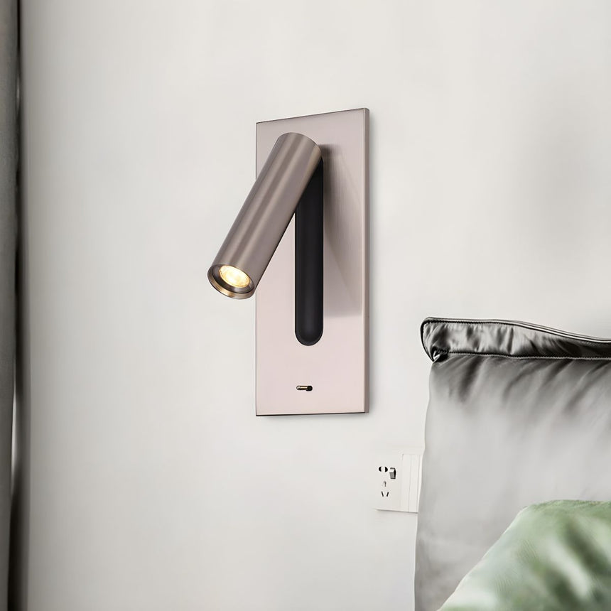 The nickel reading light above a bed with green pillows