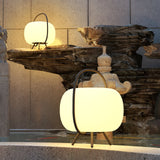 Two lamps lit beside a stone water feature on a paved terrace at night
