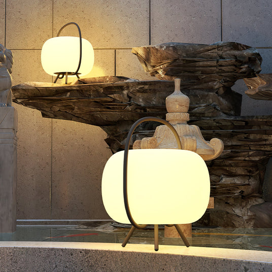 Two lamps lit beside a stone water feature on a paved terrace at night
