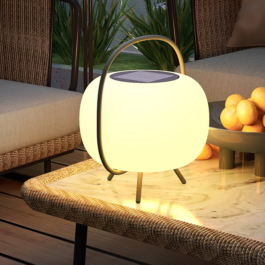 The lamp lit on a woven garden bench beside a bowl of fruit at night