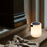 The lamp lit on a stone step beside a doorway with a linen throw on it