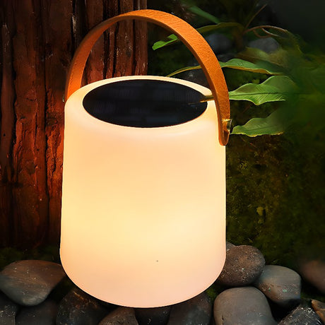 The lamp lit on river stones beside a timber post and garden planting