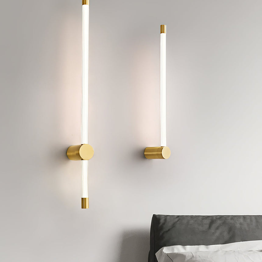 A lit pair on a bedroom wall beside a bed with dark bedding and a pale throw