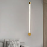 Lit beside a bed on a pale wall next to a timber panel and a knitted cushion