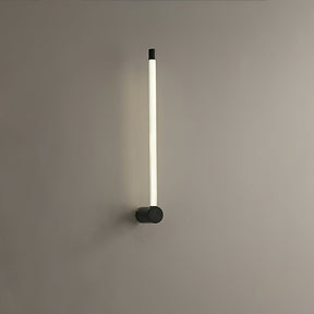The black version lit on a gray wall, the tube glowing along its full height