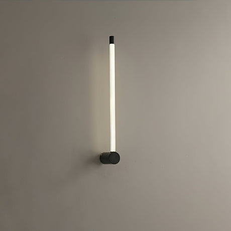 The black version lit on a gray wall, the tube glowing along its full height